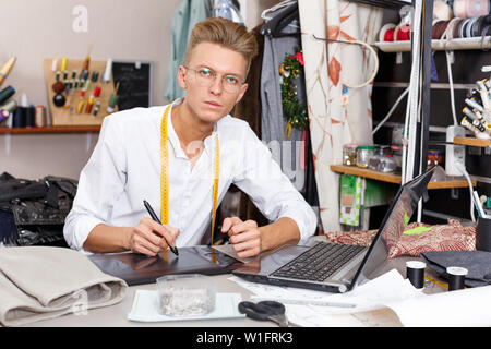 Young male tailor creating  pattern using graphics tablet at sewing atelier Stock Photo