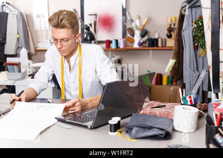 Young male tailor creating  pattern using graphics tablet at sewing atelier Stock Photo