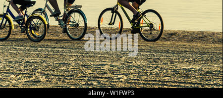 positive family rides bicycles on beach Stock Photo