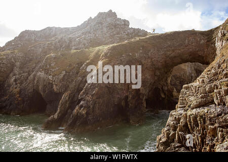 Woman standing on the edge of rock formation and natural arch due to water erosion château de Dinan, Pointe de Dinan (Beg Dinn) - Brittany - France Stock Photo