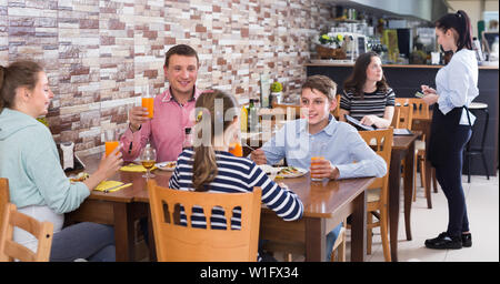 Happy family with teenagers having lunch in cozy cafe Stock Photo