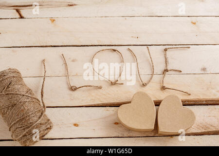 brown biodegradable gift box in heart shape with thread wrapping,lettering love made from yarn on light wood background Stock Photo
