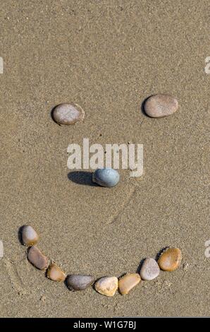 Stones forming a smiling face on the sand Stock Photo