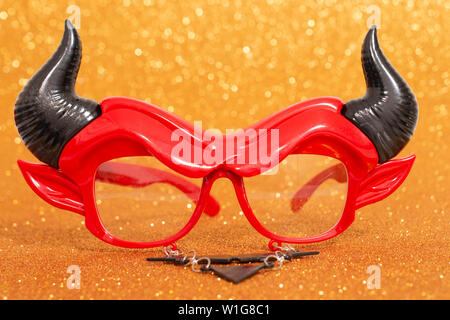 devil disguise masquerade glasses isolated on a golden background. Stock Photo
