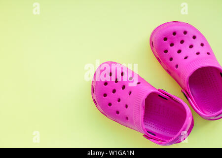San Diego, USA,May 10, 2019.Summer pink flip flops isolated on yellow background. childrens soft rubber sandals or Crocs.Summer vacation trendy shoes Stock Photo