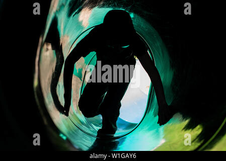 A boy climbs up a enclosed slide on a playground in the United States. Stock Photo