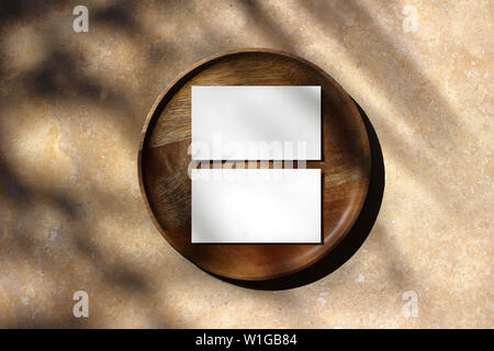 Blank white business cards mockups on wooden plate. Marble backgound with palm leaf shadow overlay. Modern template for branding identity. Tropical Stock Photo