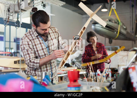 Happy male aircraft enthusiast working in workshop on creating of airplane models Stock Photo