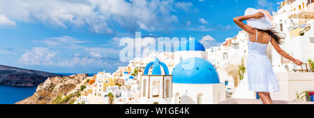 Europe tourist travel woman panorama banner from Oia, Santorini, Greece. Happy young woman looking at famous blue dome church landmark destination. Beautiful girl visiting the Greek islands. Stock Photo