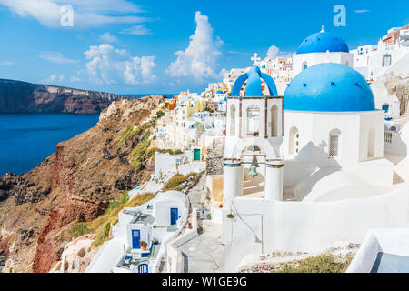 Greece famous touristic travel destination Santorini greek island. Three blue domes. Popular summer luxury vacation Europe cruise stop. Streets of European white village with the mediterranean sea. Stock Photo