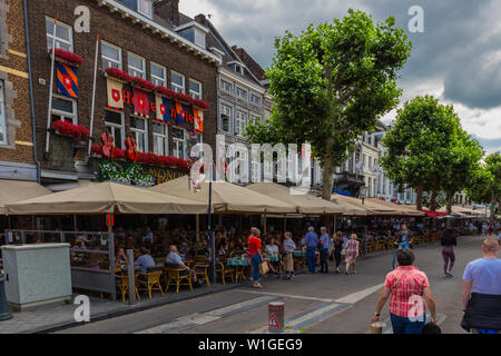 Tourist enjoying drinks and food at the terraces in downtown maastricht with dramatic sky. Stock Photo