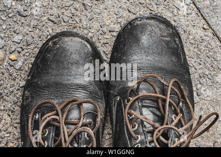 old worn out black lace shoes on a sidewalk Stock Photo