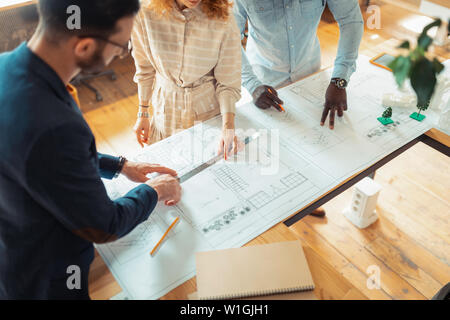 Designers drawing sketches. Top view of three experienced interior designers drawing sketches for new project Stock Photo