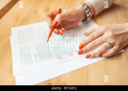 Red nails. Close up of woman with red nails making some notes in paper while working Stock Photo