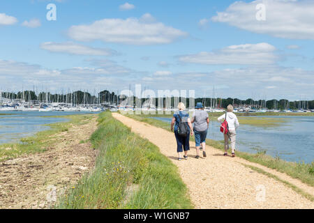 Three women walking along the Solent Way long distance path beside the Hamble River on a sunny summer day, Hampshire, UK Stock Photo