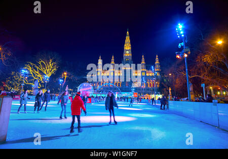 VIENNA, AUSTRIA - FEBRUARY 18, 2019: The evening Rathaus square with a view on crowded ice skating rink in front of brightly illuminated Town Hall (Ra Stock Photo