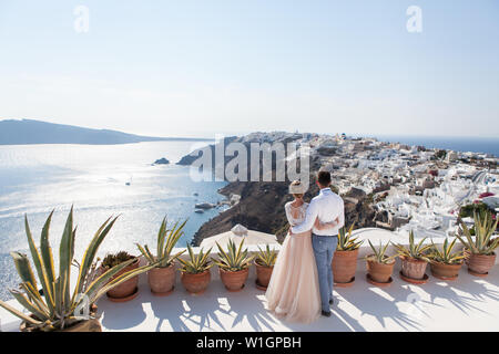 Santorini, Oia, Greece - September 10, 2018: a couple of newly married people enjoying their honeymoon months in Greece on the terrace over sea Stock Photo