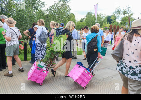 Women with exhibition plants during the festival.The Royal Horticultural Society (RHS) Hampton Court Garden Festival, showcases plant and flower exhibits at Hampton Court Palace in London. Stock Photo