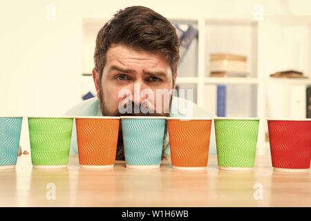 Choose from alternatives. Man bearded choosing one of lot colorful paper cups. Alternative concept. Pick one. Diversity and recycling. Eco paper cup. Coffee to go paper cup. How many cups per day. Stock Photo
