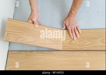 Installation of a laminate floorboard. Worker's hands are attaching one bar after another. Stock Photo