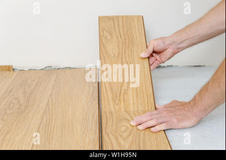 Installation of a laminate floorboard. The worker is attaching one bar after another. Stock Photo