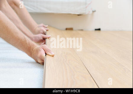 The hands of the workers are clamping  the row of boards in the floor array. Stock Photo