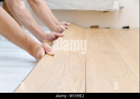 The hands of the workers are clamping  the row of boards in the floor array. Stock Photo