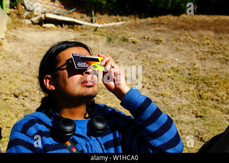 La Paz, Bolivia 2nd July 2019: A young man uses a solar eclipse filter to watch a partial eclipse of the sun at an eclipse watching event near the city centre. In La Paz the eclipse lasted for about 2 hours 10 minutes with about 55% coverage at its maximum. Stock Photo