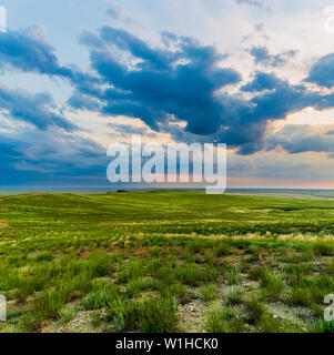 Scenic sunset with clouds in sky in steppe. Stock Photo