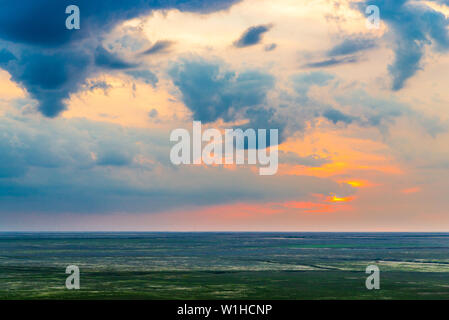 Scenic sunset with clouds in sky in steppe. Stock Photo