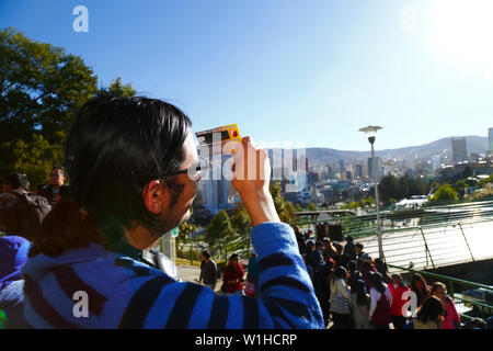 La Paz, Bolivia 2nd July 2019: A man uses a special solar eclipse filter to watch a partial eclipse of the sun at an eclipse watching event near the city centre. In La Paz the eclipse lasted for about 2 hours 10 minutes with about 55% coverage at its maximum. Stock Photo