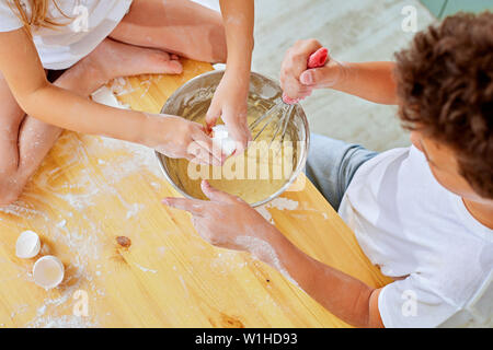 Children's small hands beat the dough for pancakes cooking in the kitchen