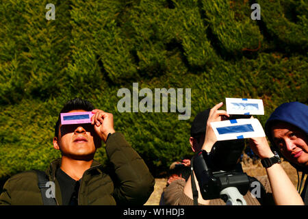 La Paz, Bolivia 2nd July 2019: People use solar eclipse filters to watch a partial eclipse of the sun at an eclipse watching event near the city centre. In La Paz the eclipse lasted for about 2 hours 10 minutes with about 55% coverage at its maximum. Stock Photo