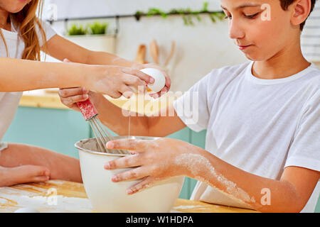 brother and sister help mother to prepare in kitchen Stock Photo