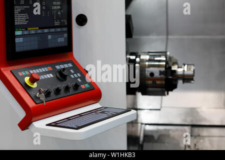 Modern CNC lathe machine with a control panel in the foreground. Selective focus. Stock Photo