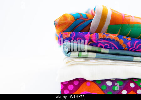 Stacked fabrics with vivid colors and patterns. Isolated on white background with negative space. Stock Photo