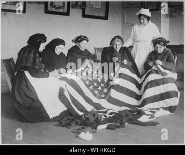 Patriotic old women make flags. Born in Hungary, Galicia, Russia, Germany, Rumania. Their flag-making instructor, Rose Radin, is standing. Underwood and Underwood., ca. 1918; General notes:  Use War and Conflict Number 504 when ordering a reproduction or requesting information about this image. Stock Photo