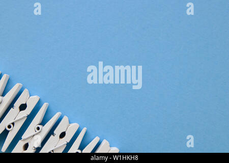 White clothespins in a row on blue background. Flat lay, negative space. Stock Photo