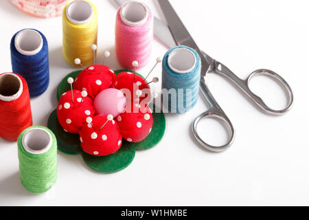 Colorful sewing items on white background, tailor's tools, needles, threads scissors, measuring tape Stock Photo