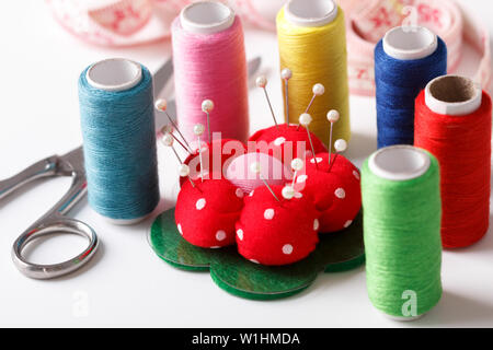 Colorful sewing items on white background, tailor's tools, needles, threads scissors, measuring tape Stock Photo