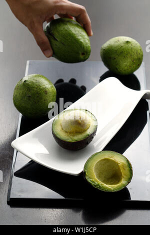 Photo of sliced avocado and hand picking up an avocado Stock Photo