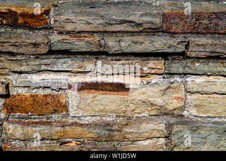 Old grungy stonewall with red grey and yellow. Strong texture for background backdrop Stock Photo