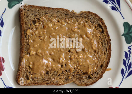 close up of Bread with peanut butter on white plate on wooden background Stock Photo