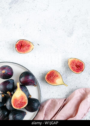 Half and whole figs on gray cement or stone background. Ripe violet figs with copy space for text. Top view or flat lay. Vertical. Stock Photo