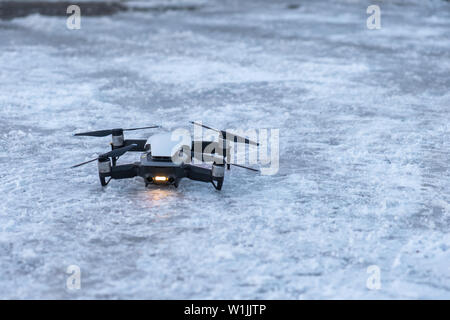 Drone Unmanned aircraft system parked standby on snowy floor Stock Photo