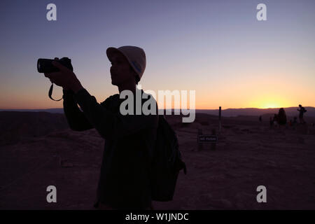 Silhouette of a photographer against sunset sky, the notice board NO PASAR behind means No Passing Stock Photo