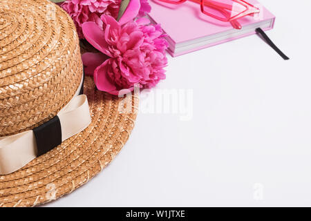Summer straw hat and pink peonies on the white table, close-up Stock Photo