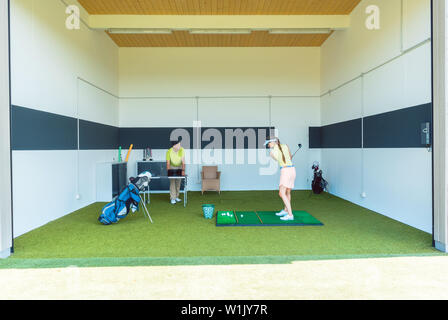 Dedicated golf coach using modern equipment while teaching a young woman Stock Photo