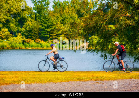 Montreal, Canada - June, 2018: Elderly Canadian couple riding bicycle near the pond in Rapids park, Montreal, Canada. Stock Photo
