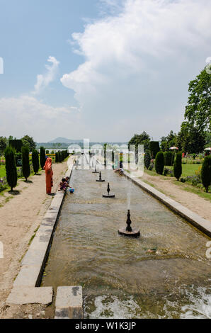 Kids and adults enjoying in the stream of water lined by fountains at Nishat Bagh, Srinagar, Jammu and Kashmir, India. Stock Photo